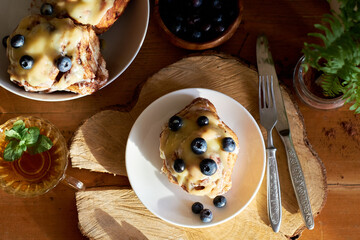 Cinnamon rolls with white chocolate and blueberries. Brioche. Side view, wooden background, icing sugar, cocoa, yeast buns.