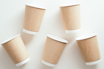 Takeaway paper cups of coffee on white background. Flat lay, top view.