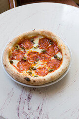 Whole round neapolitan pepperoni pizza served on a table