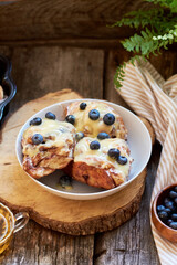 Cinnamon rolls with white chocolate and blueberries. Brioche. Side view, wooden background, icing sugar, cocoa, yeast buns.