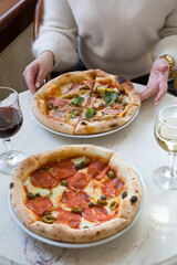 Two women eating pizzas and drinking wine