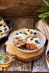 Cinnamon rolls with white chocolate and blueberries. Brioche. Side view, wooden background, icing sugar, cocoa, yeast buns.