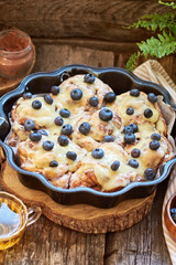 Cinnamon rolls with white chocolate and blueberries. Brioche. Side view, wooden background, icing sugar, cocoa, yeast buns.