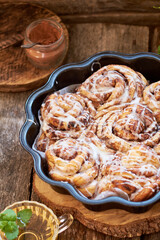 Rose cinnamon rolls. Brioche. Side view, wooden background, icing sugar, cocoa, yeast buns.
