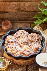 Rose cinnamon rolls. Brioche. Side view, wooden background, icing sugar, cocoa, yeast buns.