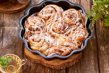 Rose cinnamon rolls. Brioche. Side view, wooden background, icing sugar, cocoa, yeast buns.