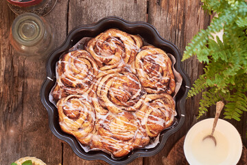Rose cinnamon rolls. Brioche. Top view, wooden background, icing sugar, cocoa, yeast buns.