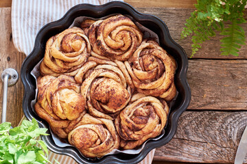 Rose cinnamon rolls. Brioche. Top view, wooden background, cocoa, yeast buns.
