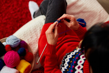 Mature female sitting in comfortable sofa and knitting