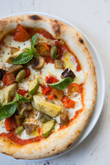 Baked neapolitan pizza with artichokes on a cafe table