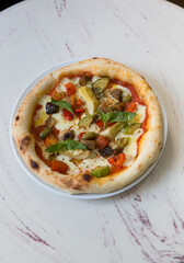 Baked neapolitan pizza with artichokes on a cafe table