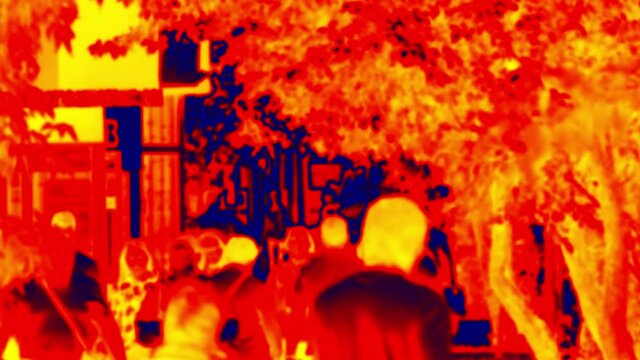 People are walking along alley on a warm summer day. Analog of thermal image. . Blurred unrecognizable people