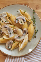 Creamy pasta with mushrooms and thyme. Top view, wooden background.