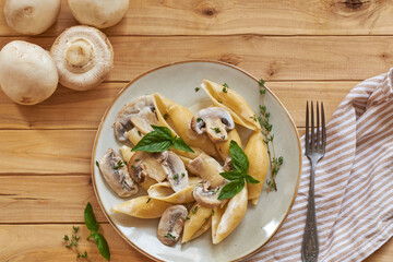 Creamy pasta with mushrooms and thyme. Top view, wooden background.