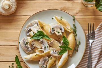 Creamy pasta with mushrooms and thyme. Top view, wooden background.