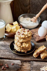 Oatmeal Chocolate Chip Cookies.  Wooden background, side view, eggs, oatmeal, flour, chocolate chips, ingredients, milk, butter, rustic.