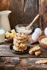 Oatmeal Chocolate Chip Cookies.  Wooden background, side view, eggs, oatmeal, flour, chocolate chips, ingredients, milk, butter, rustic.