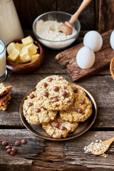 Fototapeta na wymiar Oatmeal Chocolate Chip Cookies. Wooden background, side view, eggs, oatmeal, flour, chocolate chips, ingredients, milk, butter, rustic.