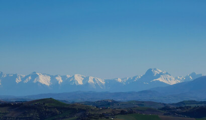 Cime innevate valli e colline dei monti appennini  nel cielo azzurro di una giornata primaverile