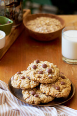 Oatmeal Chocolate Chip Cookies. Wooden table, side view, milk, chocolate, oatmeal.