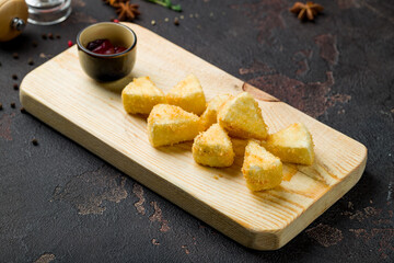deep fried cheese with berry sauce on board on brown concrete table