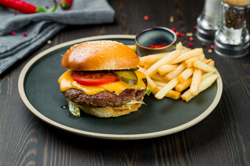 Burger with meat, french fries and ketchup on dark wooden table