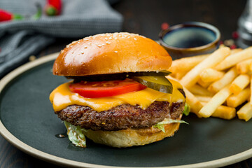 Burger with meat, french fries and ketchup close up on dark wooden table