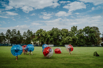 People playing in Bubble Football. Zorbing bumper football soccer on a green field