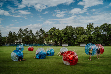 People playing in Bubble Football. Zorbing bumper football soccer on a green field