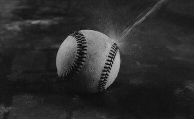 Dark moody baseball ball close up with water in black and white for rain concept.