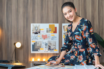 portrait of asian female woman entrepreneur smile with confident and cheerul looking at camera with background of material sample chart home office background