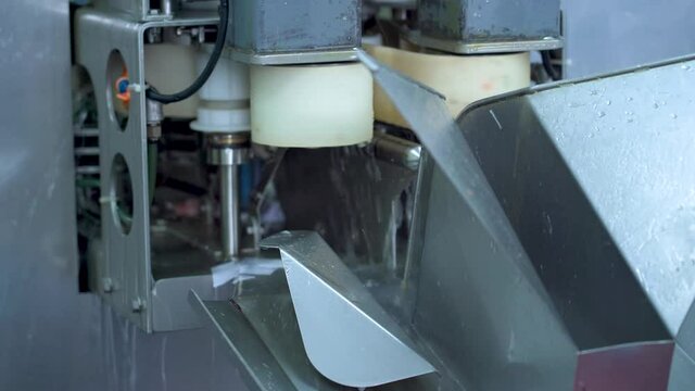 Fish processing at a factory. A salmon filleting machine. A close-up of a salmon carcass cut into two pieces. A worker's hands in blue gloves lift the sliced ​​salmon fillet.