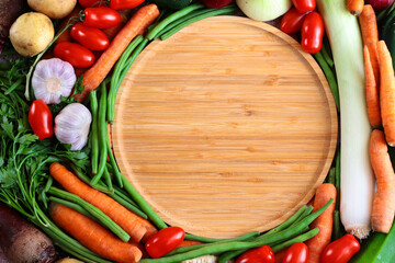 Drewniana taca otoczona warzywami. Składniki potraw wegetariańskich, produkty organiczne. Tło kulinarne - obrazy, fototapety, plakaty