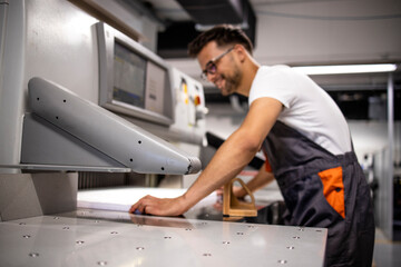 Operator working on paper cut machine in printing factory.