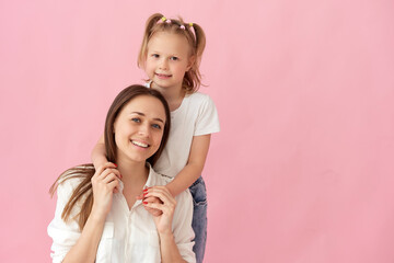 Close up photo of a beautiful young mother hugging her little daughter. best friends hugs, sincere heart feelings isolated on pastel pink colored background