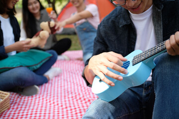 Happy friends picnic, Man playing a guitar having fun outdoor.