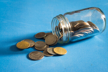 Coins with glass jar on table.