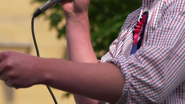 Politician wearing rosette making speech with microphone 