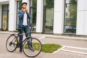 Wide shot portrait of handsome young man putting helmet on head before going to go ride by bicycle...