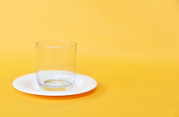 Empty small white plate and glass isolated on yellow background