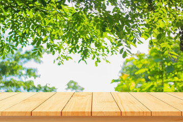 Wood floor with blurred trees of nature park background and summer season, product display montage