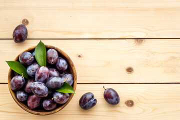 Purple plums with leaves top view. Food fruits background