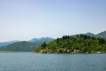 Landscape with lake and green mountains against the background of a clear sky. Panoramic beautiful view on largest lake. Wonderful summer day.