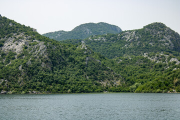 Fototapeta na wymiar Croup of green mountains around beautiful lake. Landscape on the natural park highlands. Panoramic view on the lake shore.