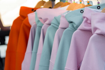 Closeup photo of colorful hoodies hanging in row for sell, A hoodie is a sweatshirt with a hood