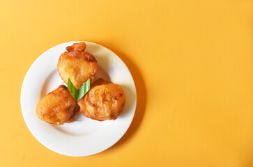 Crispy fried banana served on small white plate on color background