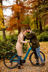 Plakat Young couple in the autumn park with electrical bicycle