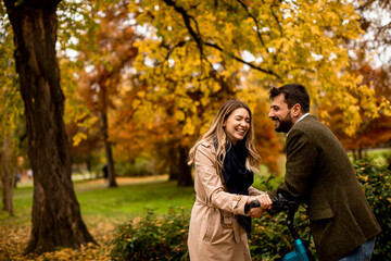 Fototapeta premium Young couple in the autumn park with electrical bicycle
