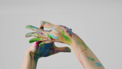 Two raised hands painted in different colors gently touch each other. Close up of dancer's palms with rainbow makeup moving emotionally over their head. Isolated