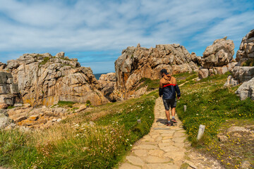 A young tourist walking the trails of Le Gouffre de Plougrescant, Cote de Granit Rose, Cotes d'Armor, Brittany, France - obrazy, fototapety, plakaty